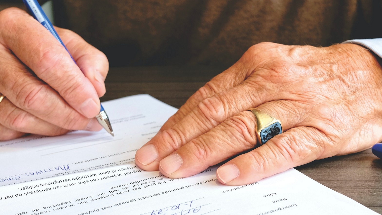 Hands signing an estate document