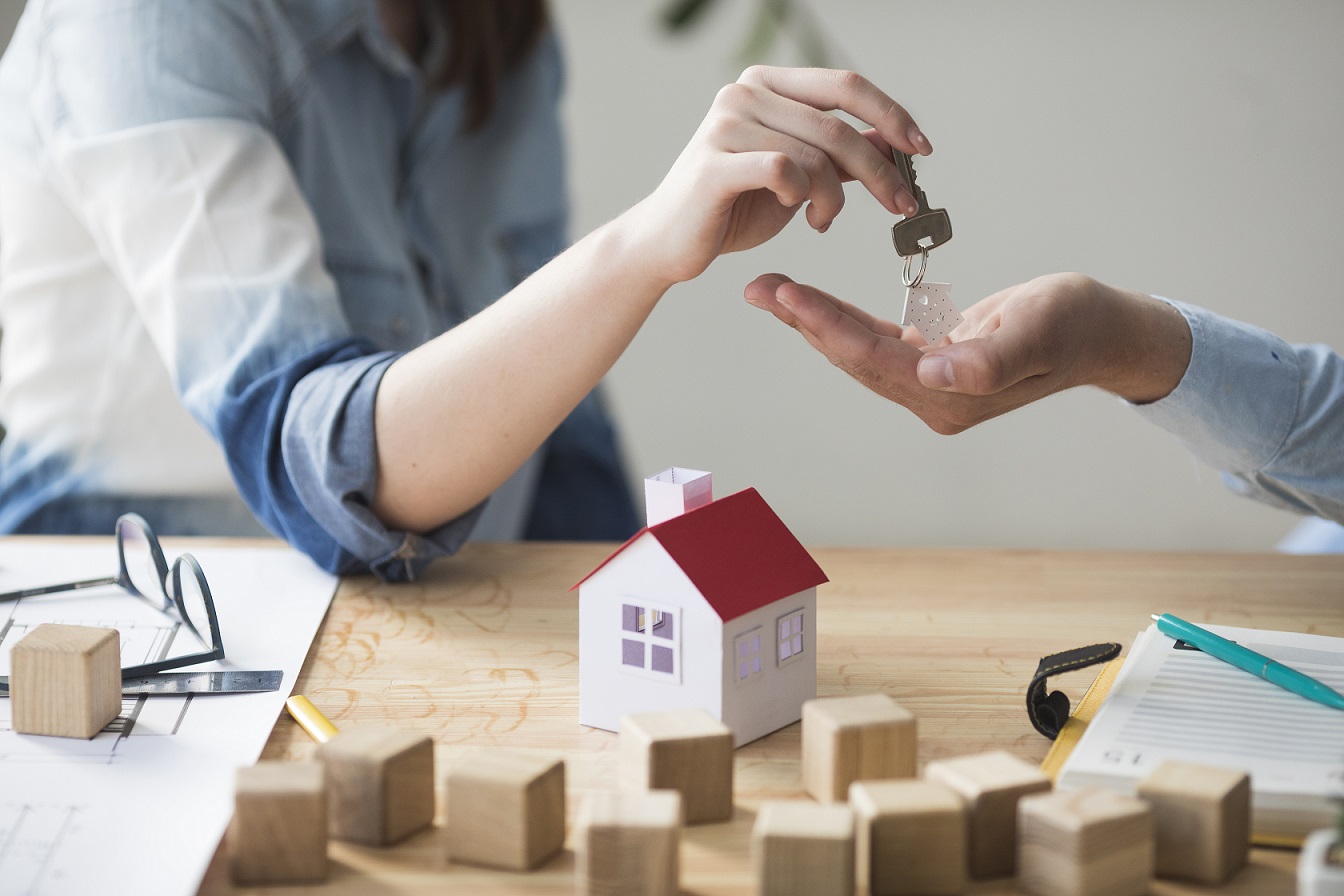 Hands exchanging house keys over a desk